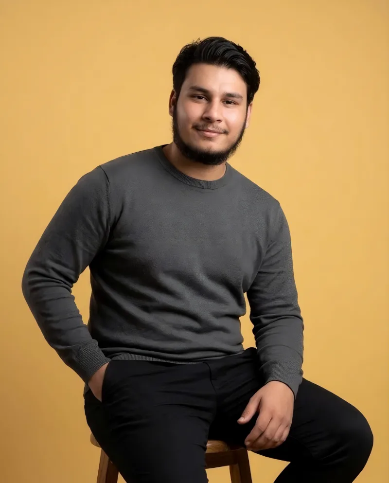 Zeeshan Ahmed, smiling, in a grey sweater.